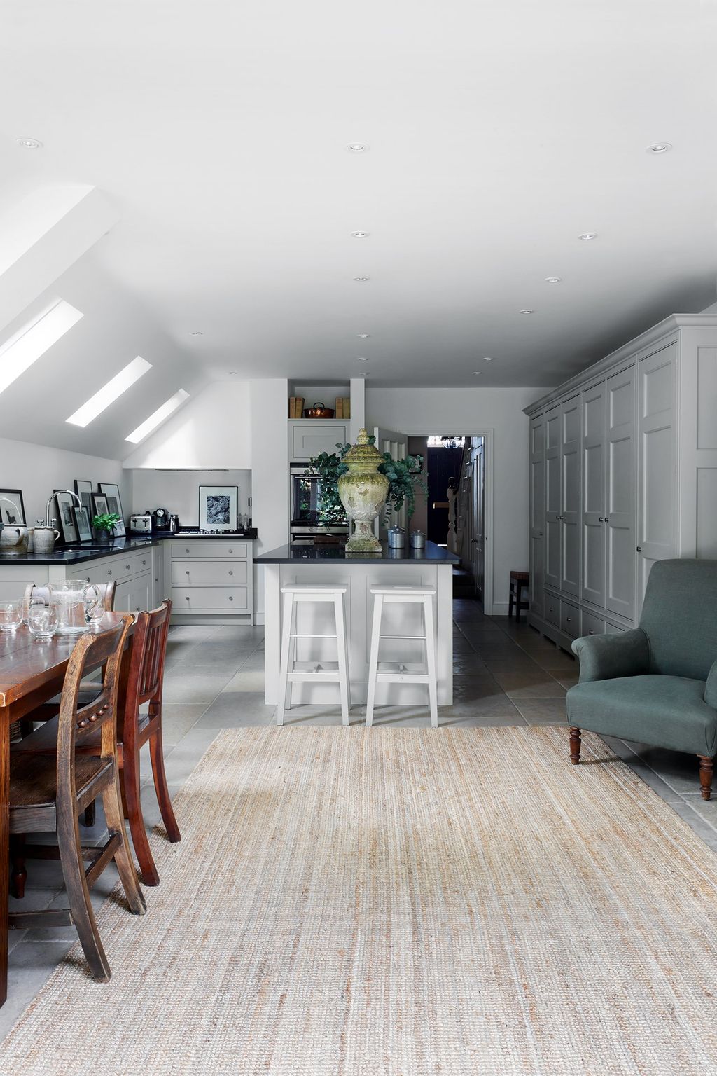 Part of the kitchen has a sloped ceiling beneath which black and white photographs are lined up along the granite worktops.