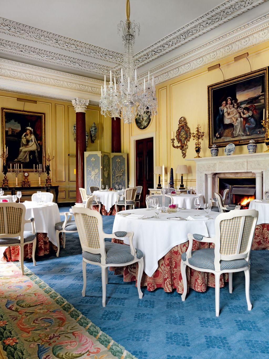 Image may contain Home Decor Furniture Chair Indoors Room Tablecloth Rug Dining Table Table Lamp and Chandelier