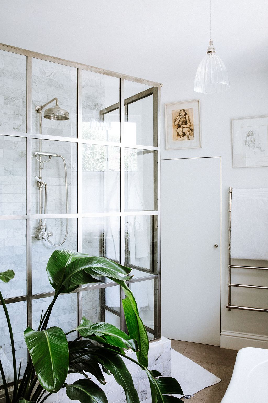 A ficus plant adds greenery to the master bathroom where a large crittal shower was designed by Gina Brennan for the space.