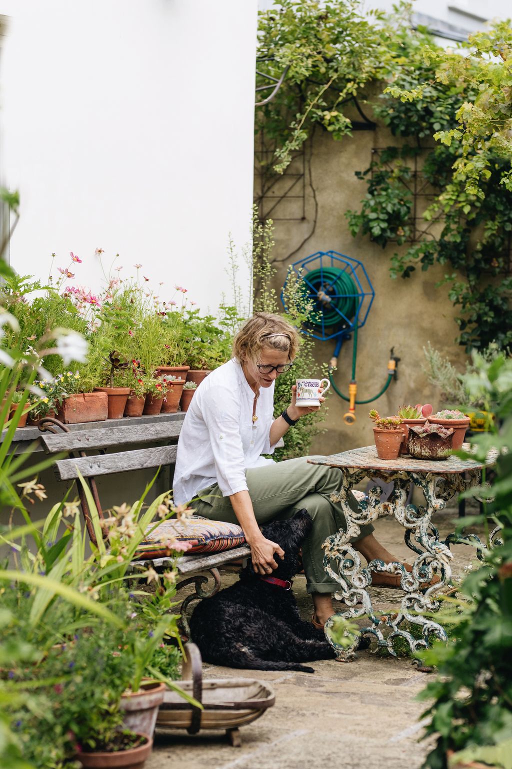 Daisy enjoys a rare tea break in her garden with Poppy the familys goldendoodle with a display of Cosmos bipinnatus...