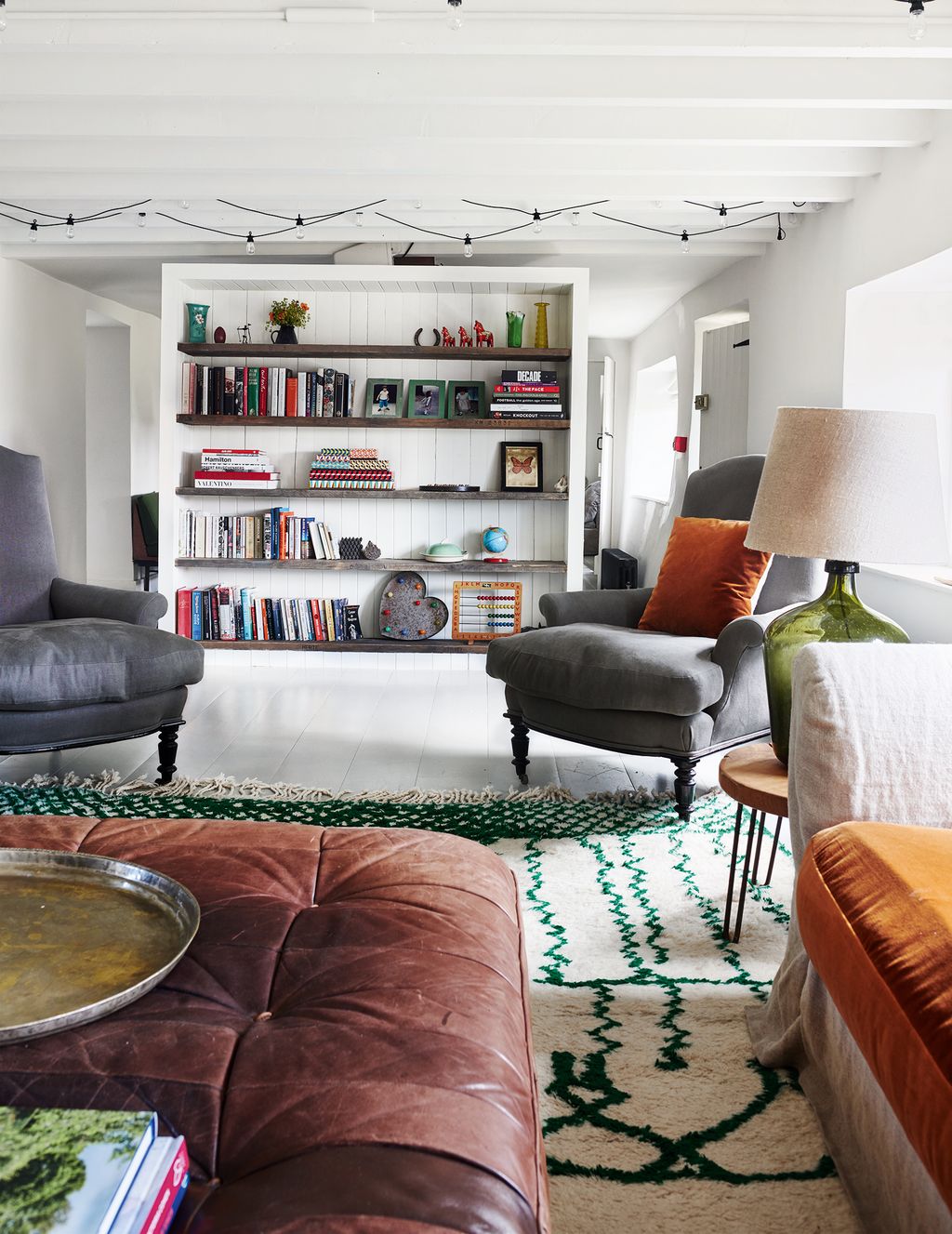 Elegant armchairs covered in CC Milano's 'Bolgheri' linen in lontra are positioned in front of bookshelves made from...