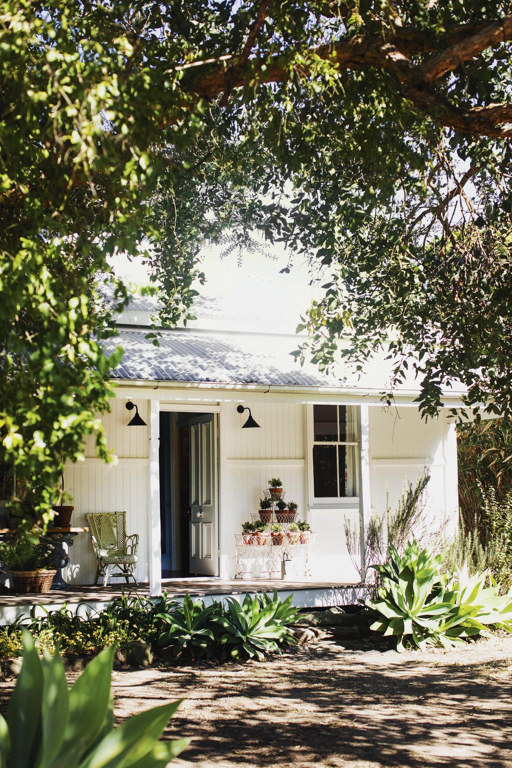 An antique plant stand holds a display of pots.