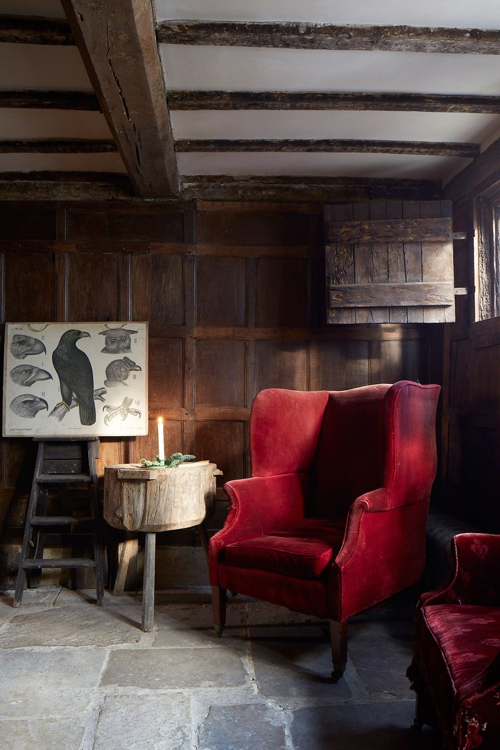 A Georgian wingback chair sits in the hall of the Tudor house where an old French butcher's block is used as a side table.