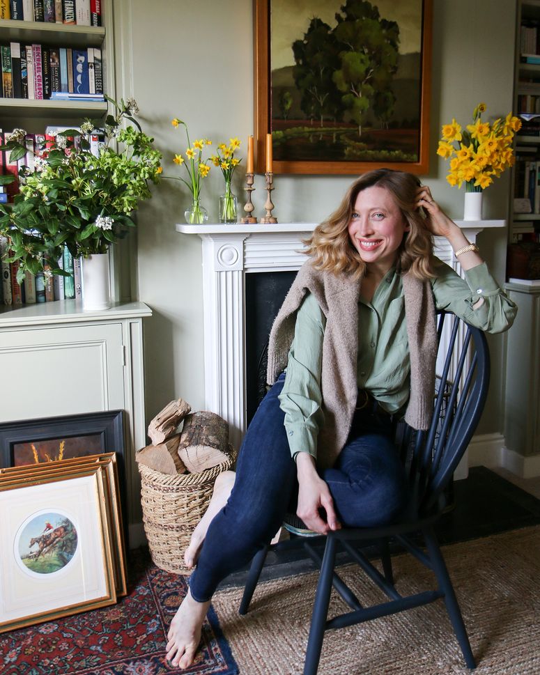 Image may contain: Furniture, Chair, Plant, Human, Person, Home Decor, Flower, Blossom, Wood, Indoors, and Flower Arrangement