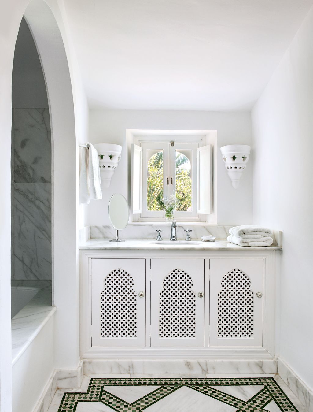 The bathroom has a Moorish feel with its marble bath alcove and Moroccanstyle cupboards and tiled floor designed by Susan.
