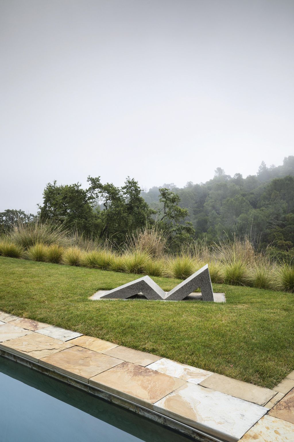 A stone sculpture by Scott Burton makes a simple yet elegant statement beside the pool.