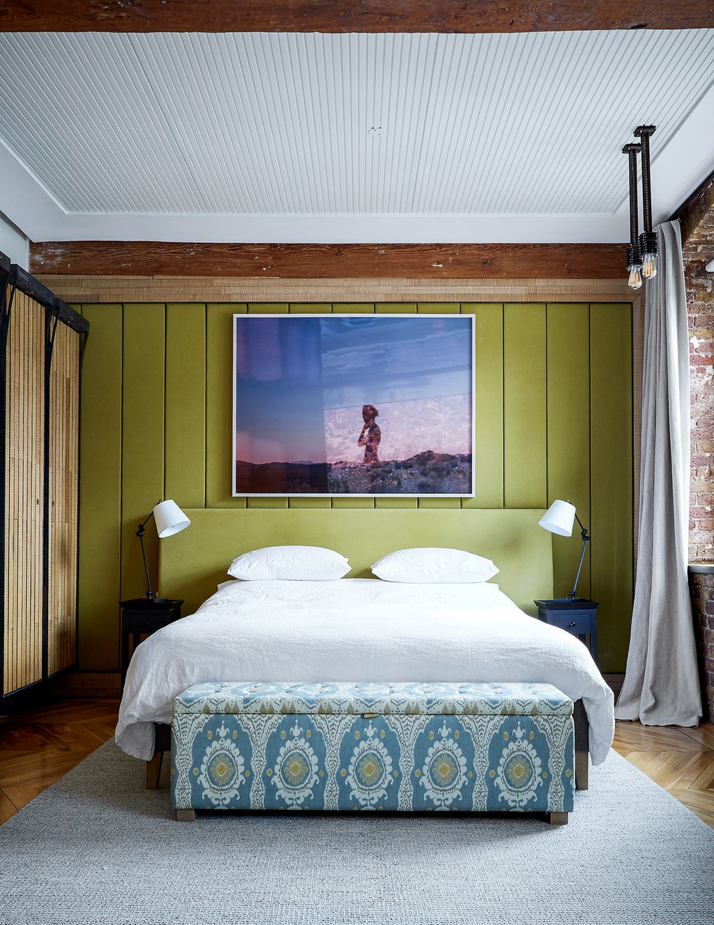 The headboard is upholstered in brushed cotton in the master bedroom with a patterned ottoman at the foot of the bed...