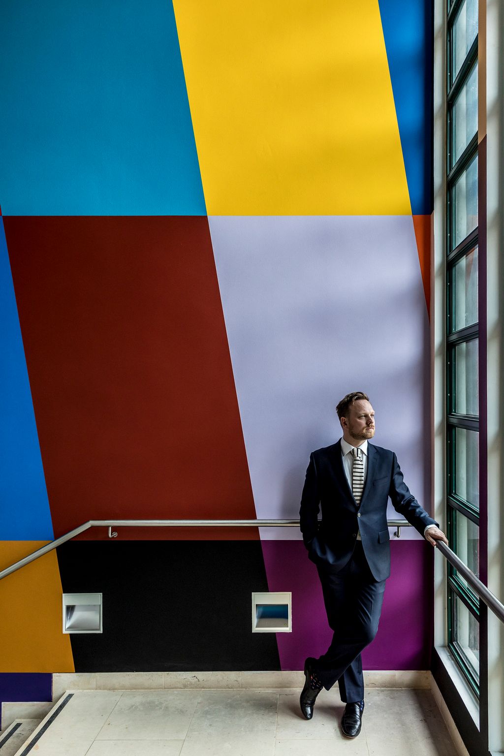 Image may contain Clothing Shoe Footwear Apparel Suit Coat Overcoat Banister Handrail Human Person and Sleeve