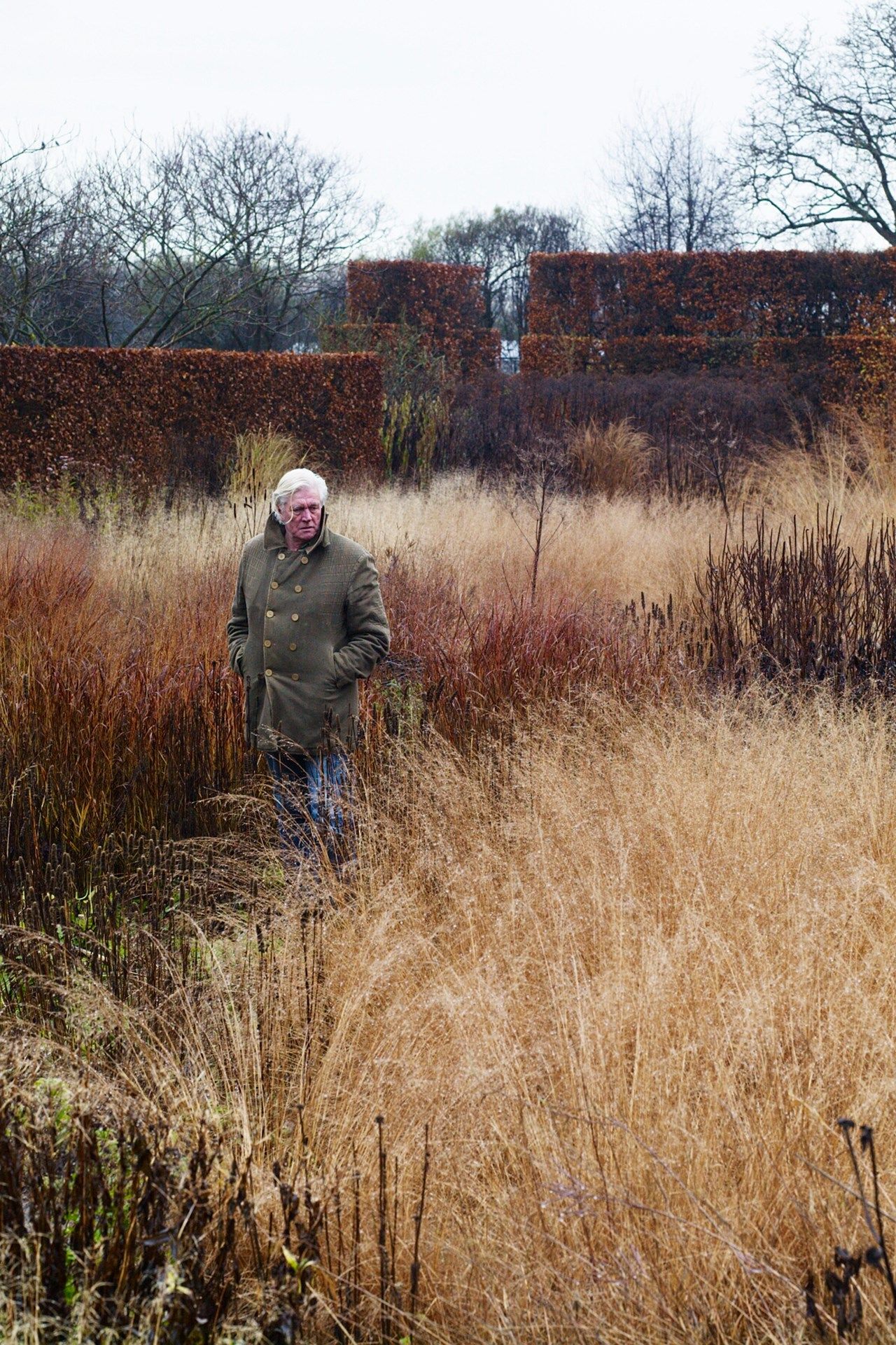 Piet deep among grasses and seed heads in the garden at the front of his home at Hummelo