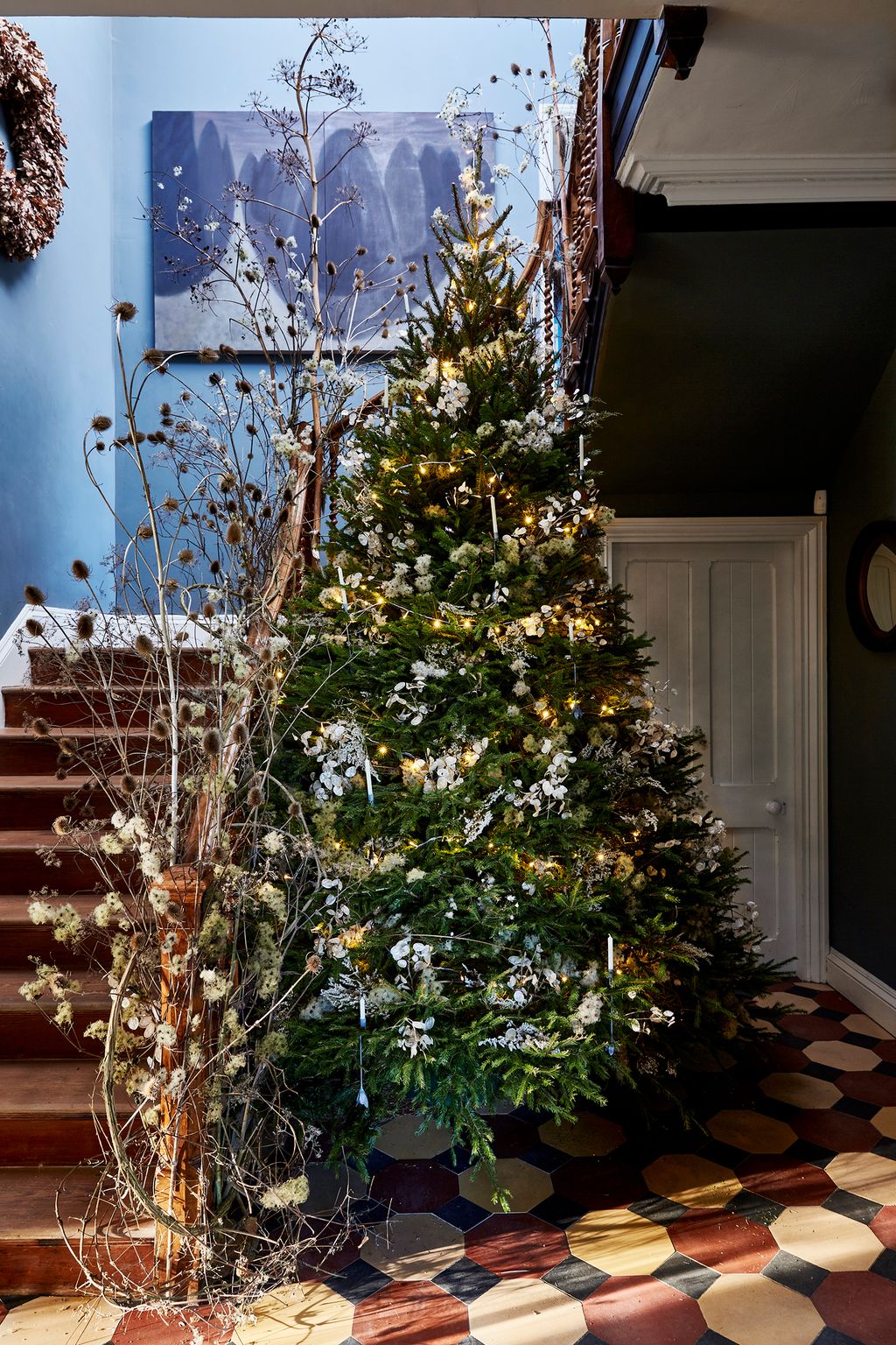The more formal tree in the hall of Pascale Smets house is decorated with foliage and candles.