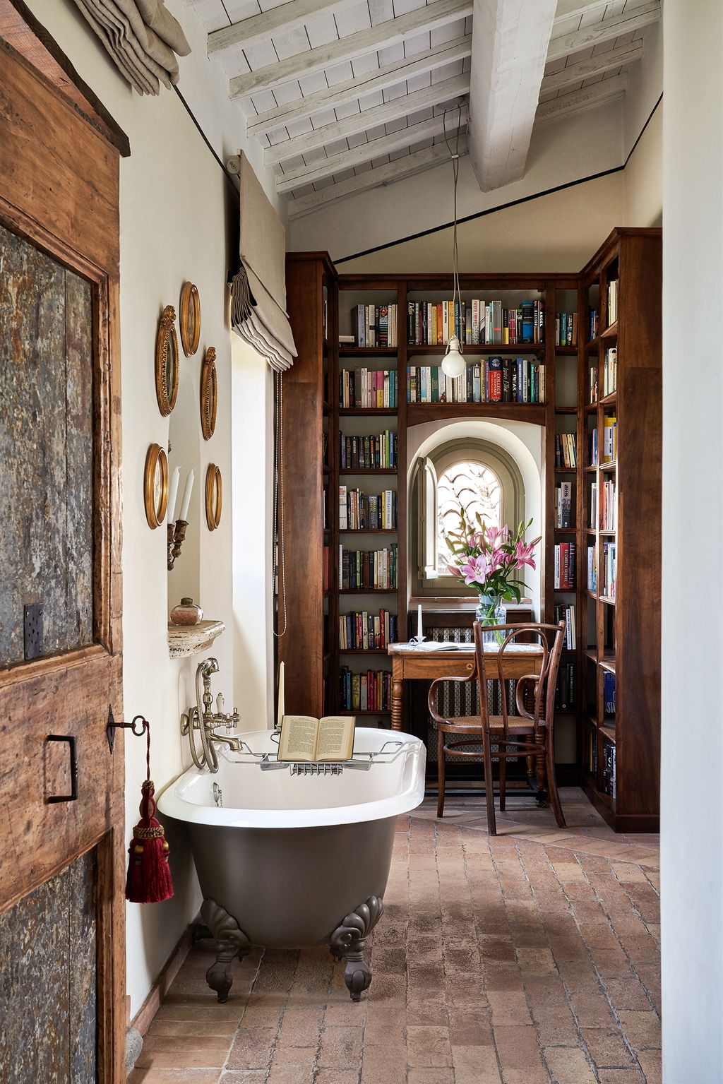 Corte della Maestàs main bedroom La Badessa features a freestanding bathtub alongside an alcove of books.