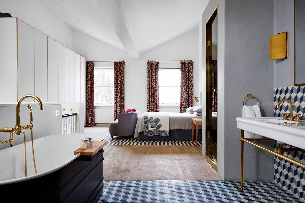 Wideplank oak floorboards and geometric tiles create a division between the openplan main bedroom and bathroom on the...