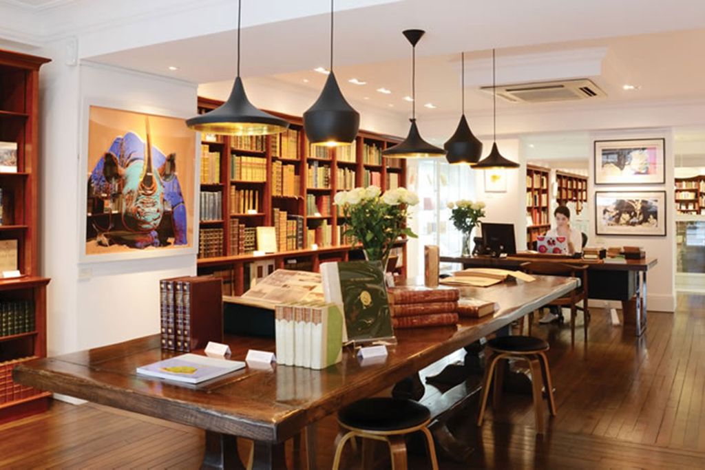 Image may contain Room Indoors Furniture Chair Wood Human Person Book Library Interior Design and Dining Table