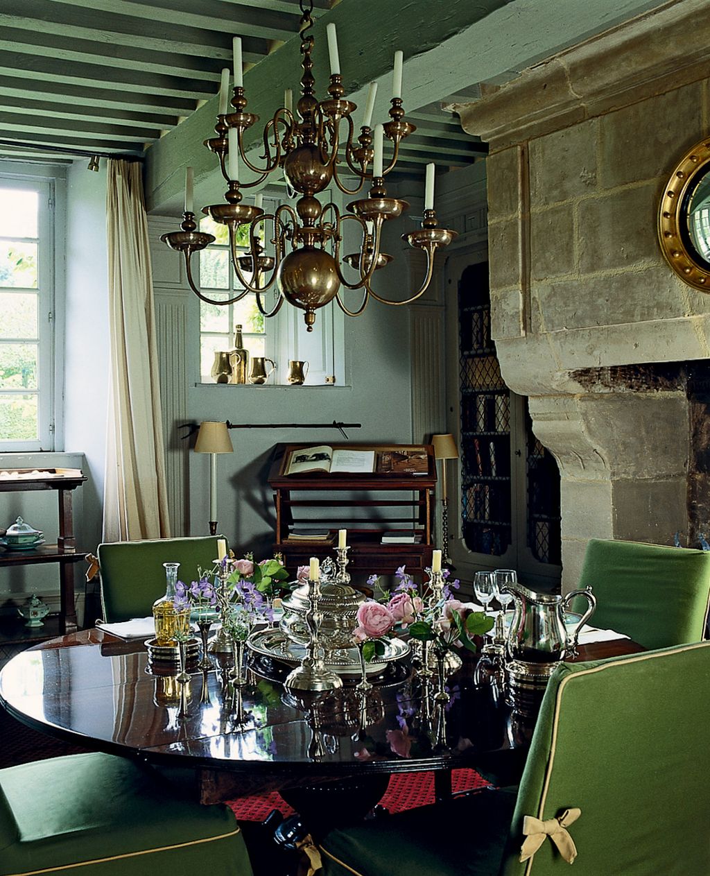 The restrained space of the dining room has elegant decorative touches such as the brass chandelier and velvetcovered...