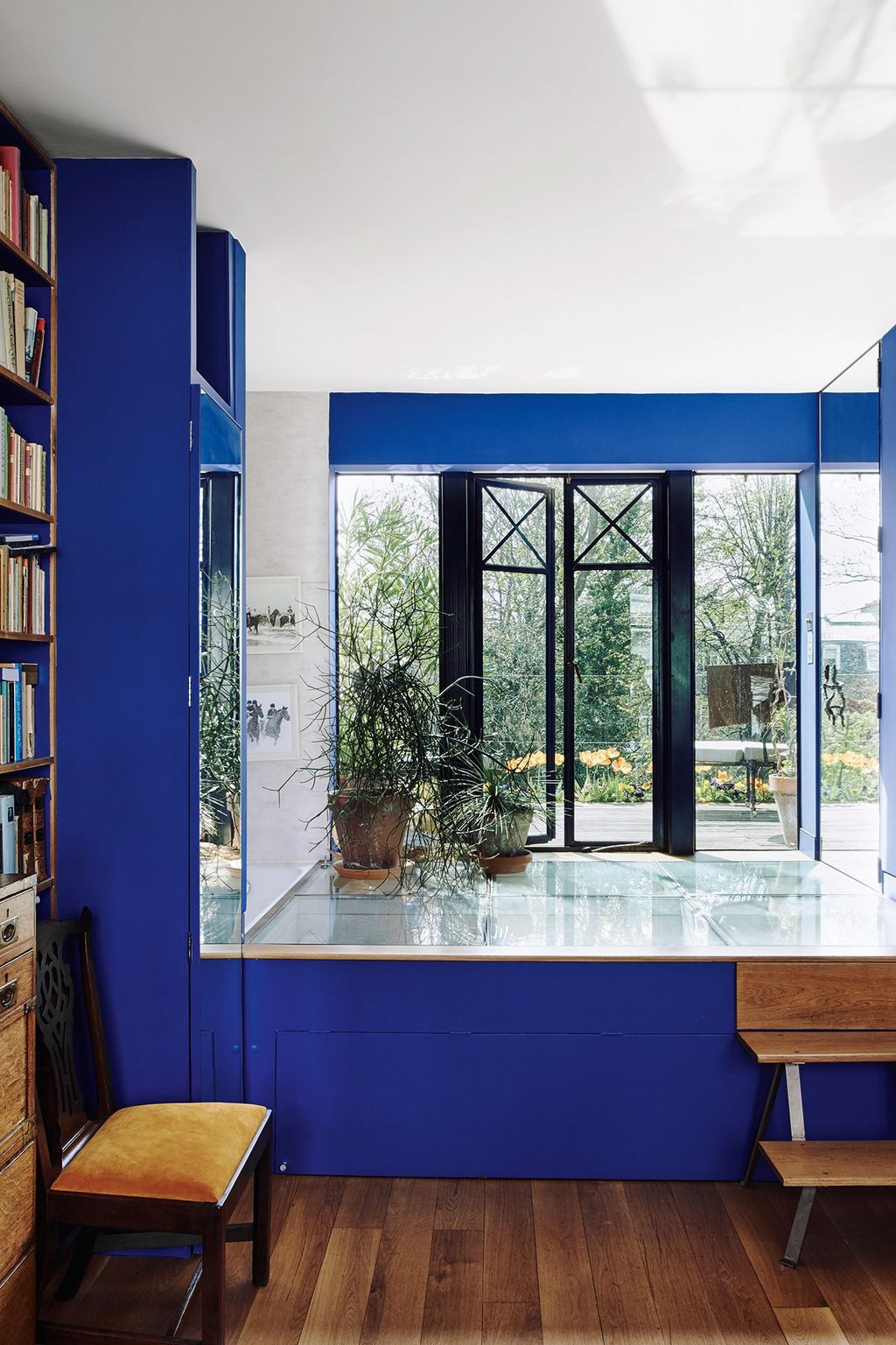 On the first floor is the electric blue dressing room painted in 'Bleu Royale' from Zuber with steps leading up to the...