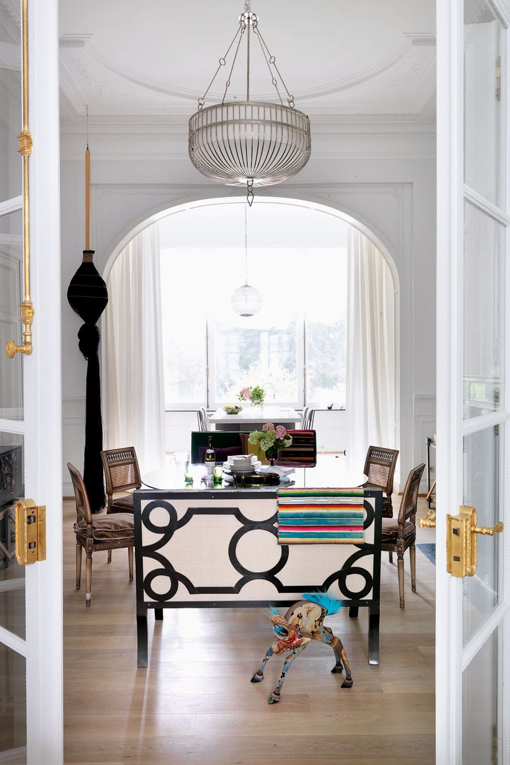 A large artwork by Susan Plum designed to resemble a Mexican woman's hair hangs next to the arch between the dining room...