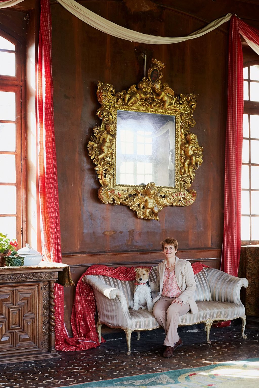 Amelie and her fox terrier Gyulai in the drawing room at the Château de Sully. The plaster walls have a trompe l'œil...