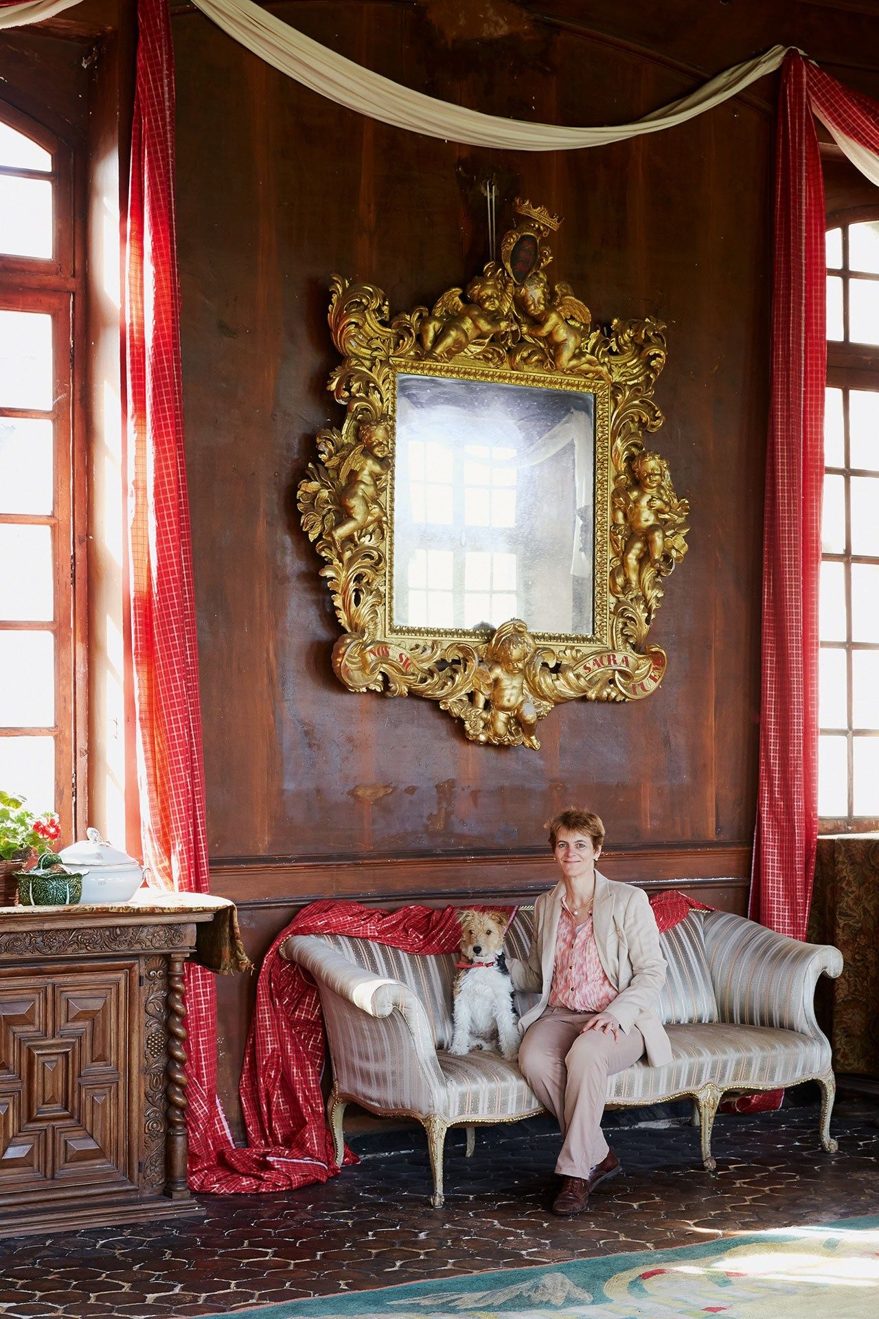 Amelie and her fox terrier Gyulai in the drawing room. The plaster walls have a trompe l'œil design to make them look...