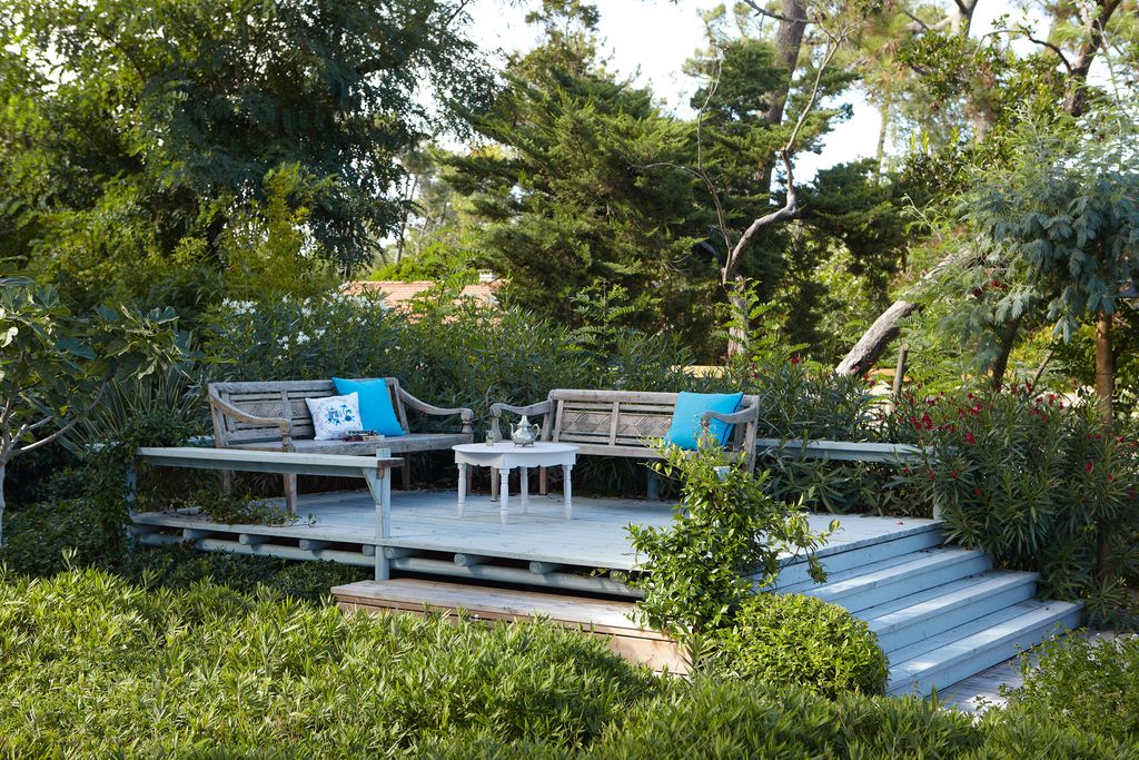 The raised terrace in the garden is positioned to afford views of the dunes and furnished with wooden benches sourced by...