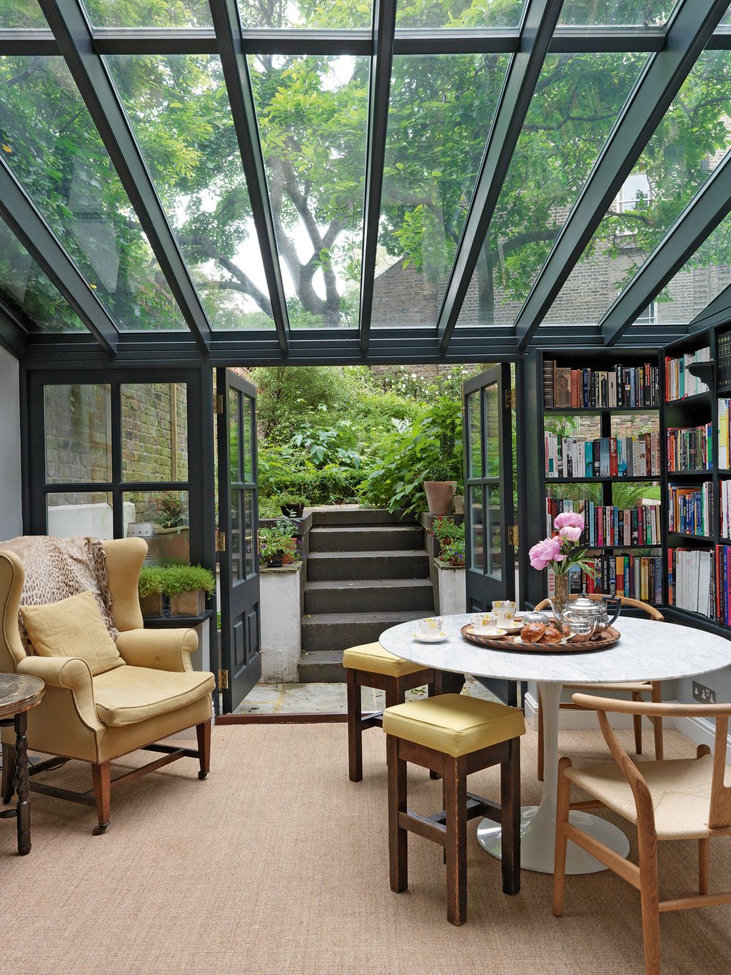 The conservatory beyond is used as a library and snug coir matting and bookcases painted in Farrow  Ball's 'Off Black...