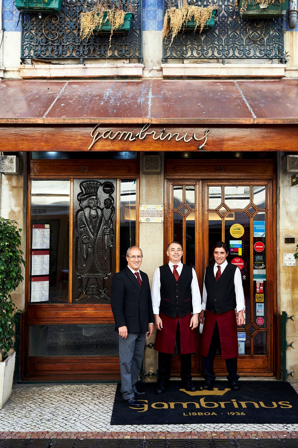 Image may contain Human Person Door Suit Coat Clothing Overcoat Apparel and Pants