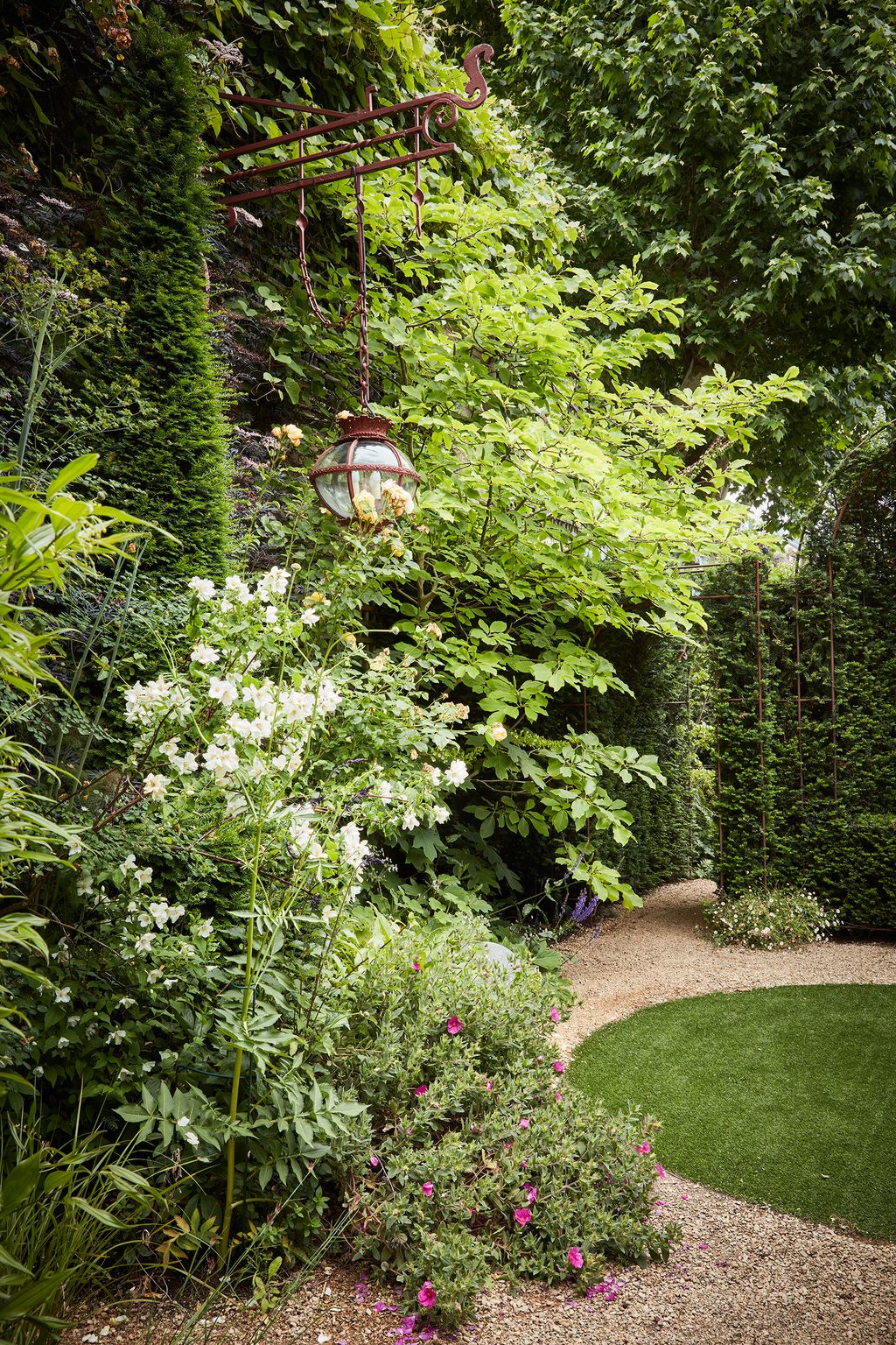 A lush tangle of flowers and foliage from the walltrained shrubs creates a richly textured scheme.