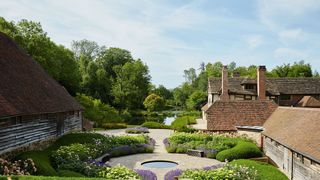 Image may contain Outdoors Grass Plant Garden Hedge Fence Water Building and Arbour