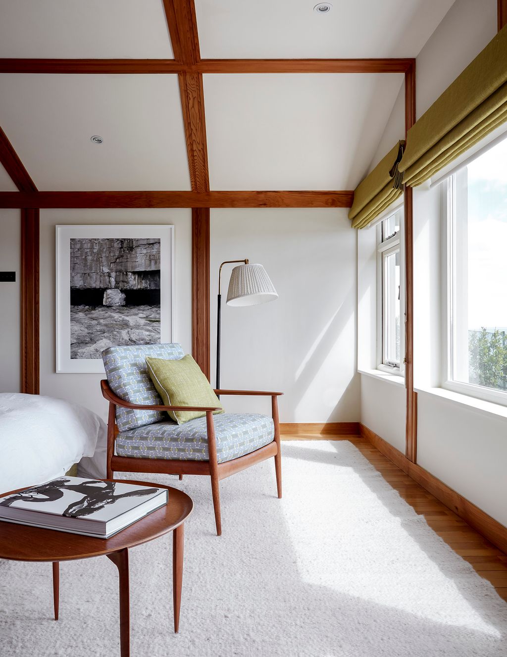 Blinds made from Fermoies ‘Plain Linen in euphorbia frame the picture windows. The vintage Knoll armchair is one of a...