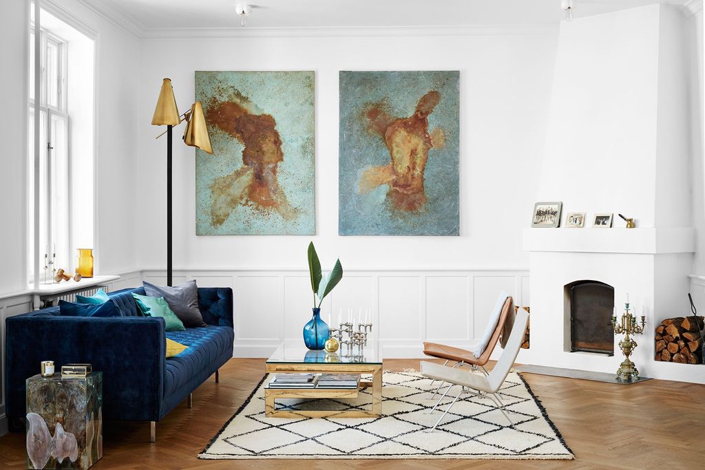 The white living room features a blue velvet sofa which adds cosiness to the modern scheme. Similar velvet cushion...