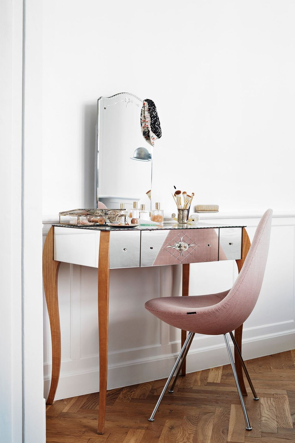 An elegant dressing table with mirrored surfaces makes the corner of this room feel spacious.