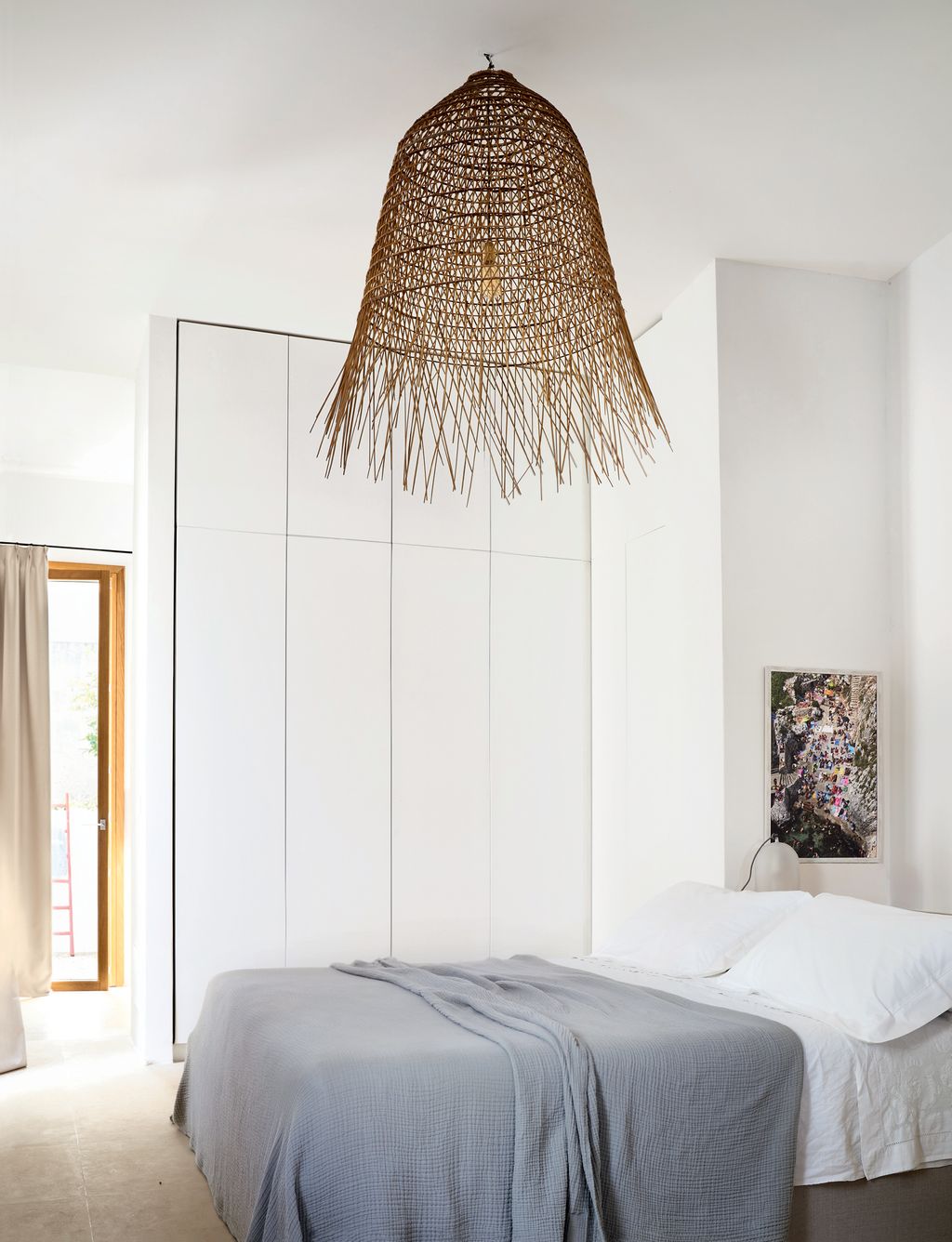 Builtin cabinetry provides plenty of storage space in this paredback bedroom overlooking the courtyard. The woven rush...