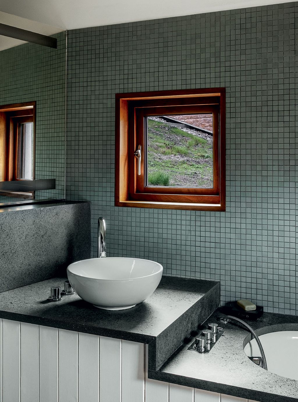 Walls in grey mosaic tiles tiered surfaces in dark basalt and white tongueandgroove panelling create a strong graphic look.