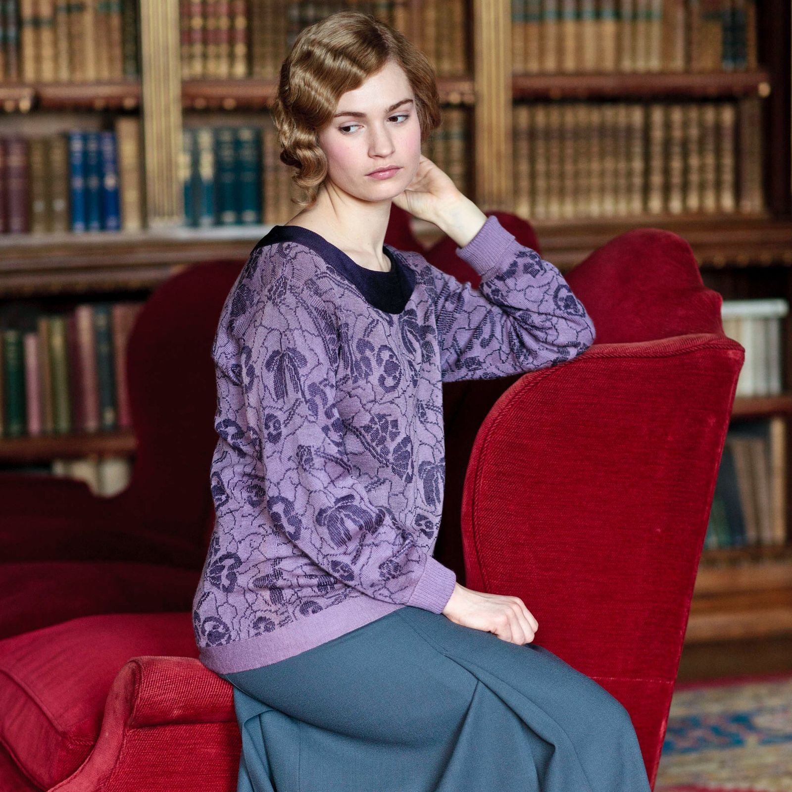 Image may contain Furniture Lily James Home Decor Bookcase Shelf Human Person Room Indoors Book Library and Couch