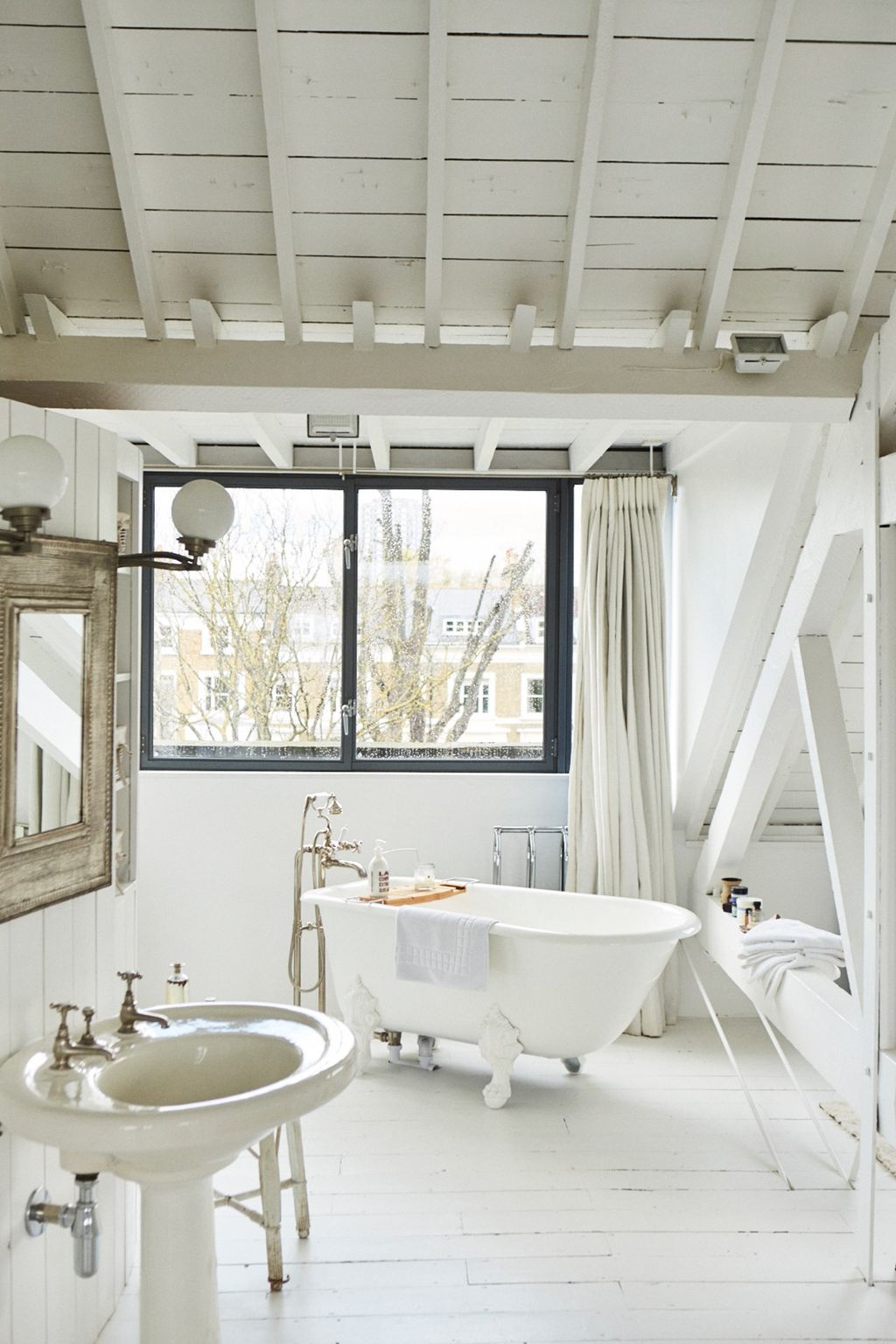 A bathroom is in an open area with exposed beams in Holland Park.