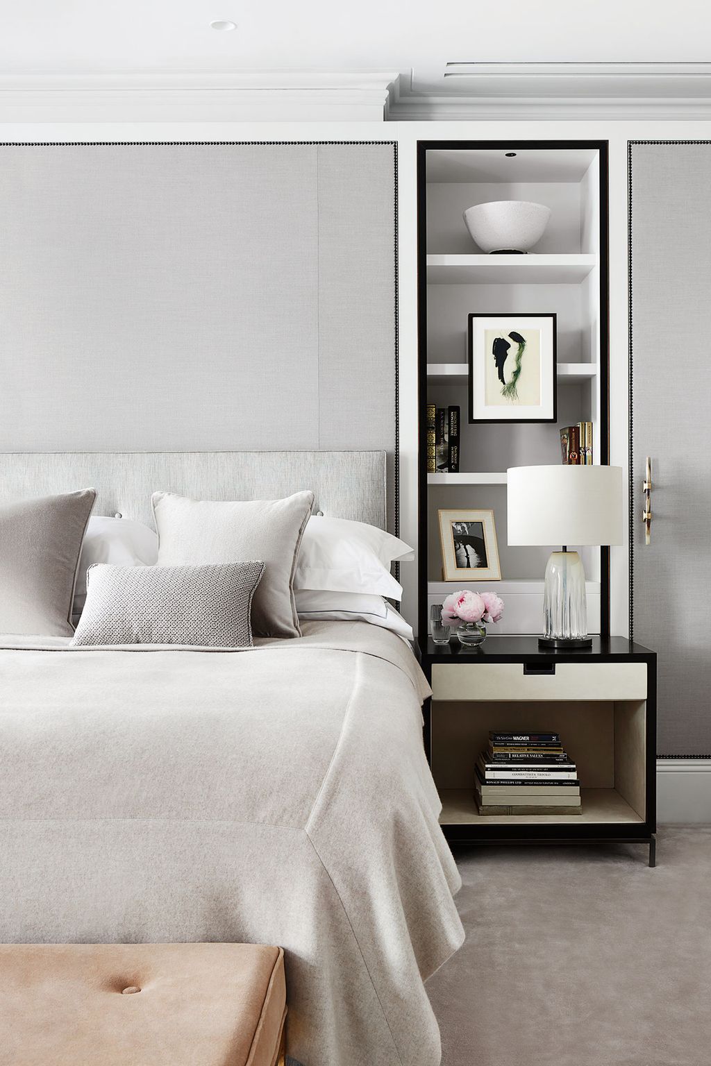 Bronze stud detailing defines the edges of the wardrobe and headboard. This framing device is complemented by the black...