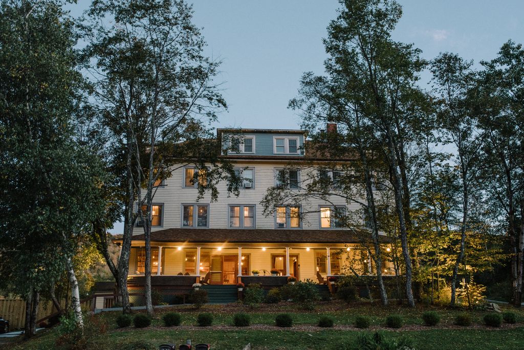 an inn at dusk with lights on the front porch