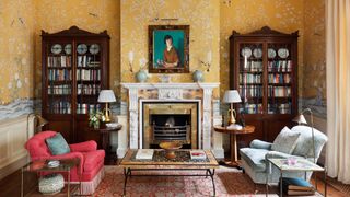 Image may contain Furniture Living Room Room Indoors Fireplace Interior Design Bookcase Shelf Human and Person