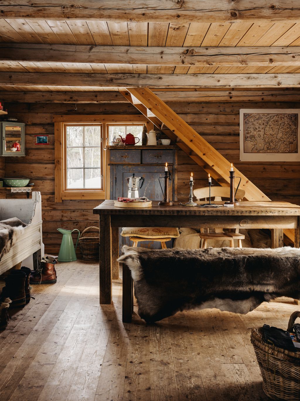 Another view of the dining area with stairs leading up to the mezzanine sleeping area. Reindeer skins are draped over...