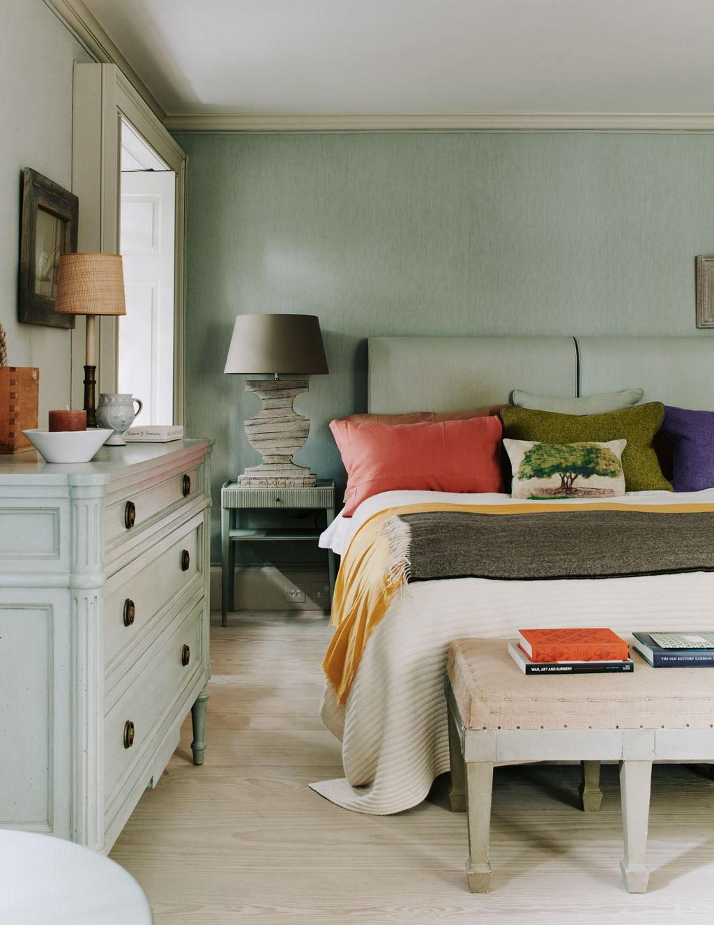 The walls in this bedroom are covered in an aqua linen which continues onto the headboard made by Jon Rhodes.  The side...