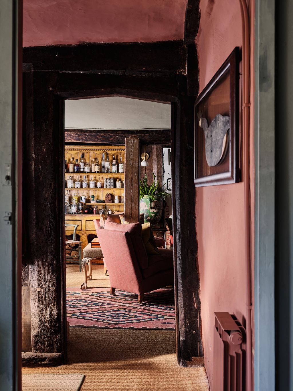 Looking into the sitting room from the snug. The entrance hall in between is painted in ‘Sang de Boeuf by Edward Bulmer...