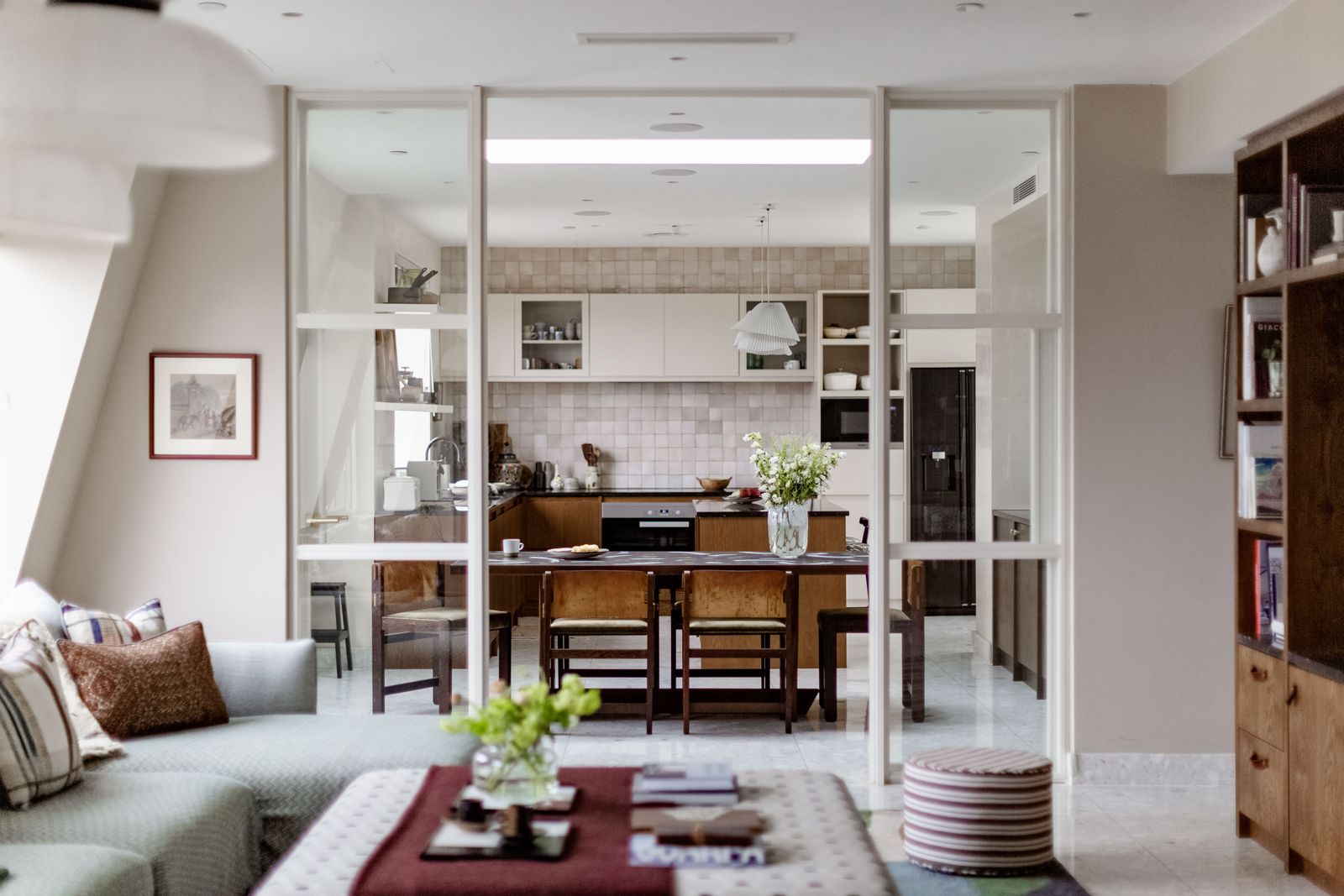 The large open plan sitting room and kitchen is separated by glass doors. The rug is a custom design by Lishan from...