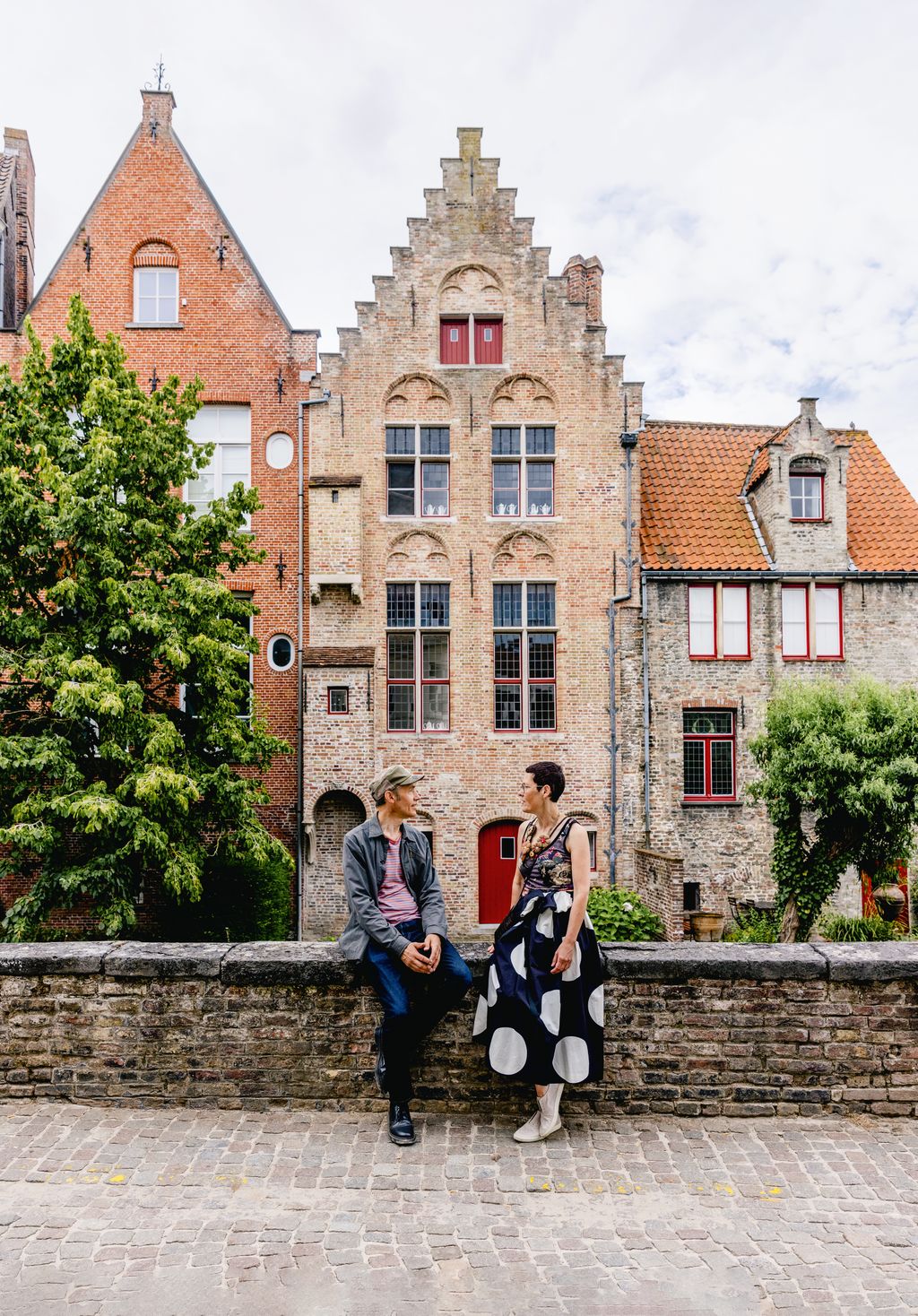 The couple beside the canal in the historic heart of Bruges  the distinctive townhouse behind them dates back to 1530