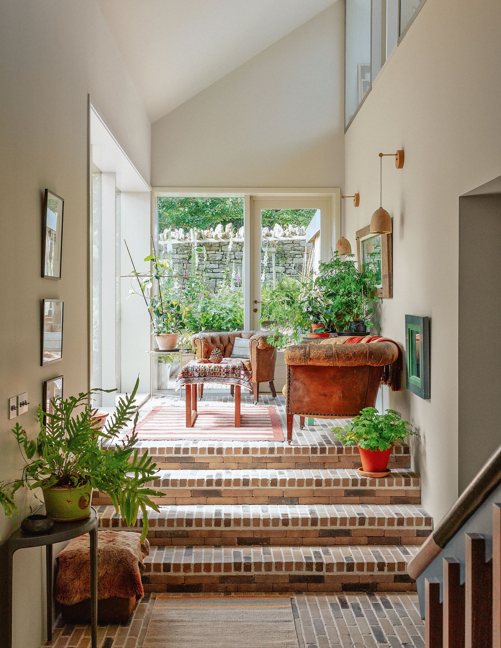 Vintage Chesterfield armchairs in front of southfacing windows onto the garden offer an inviting spot to relax.