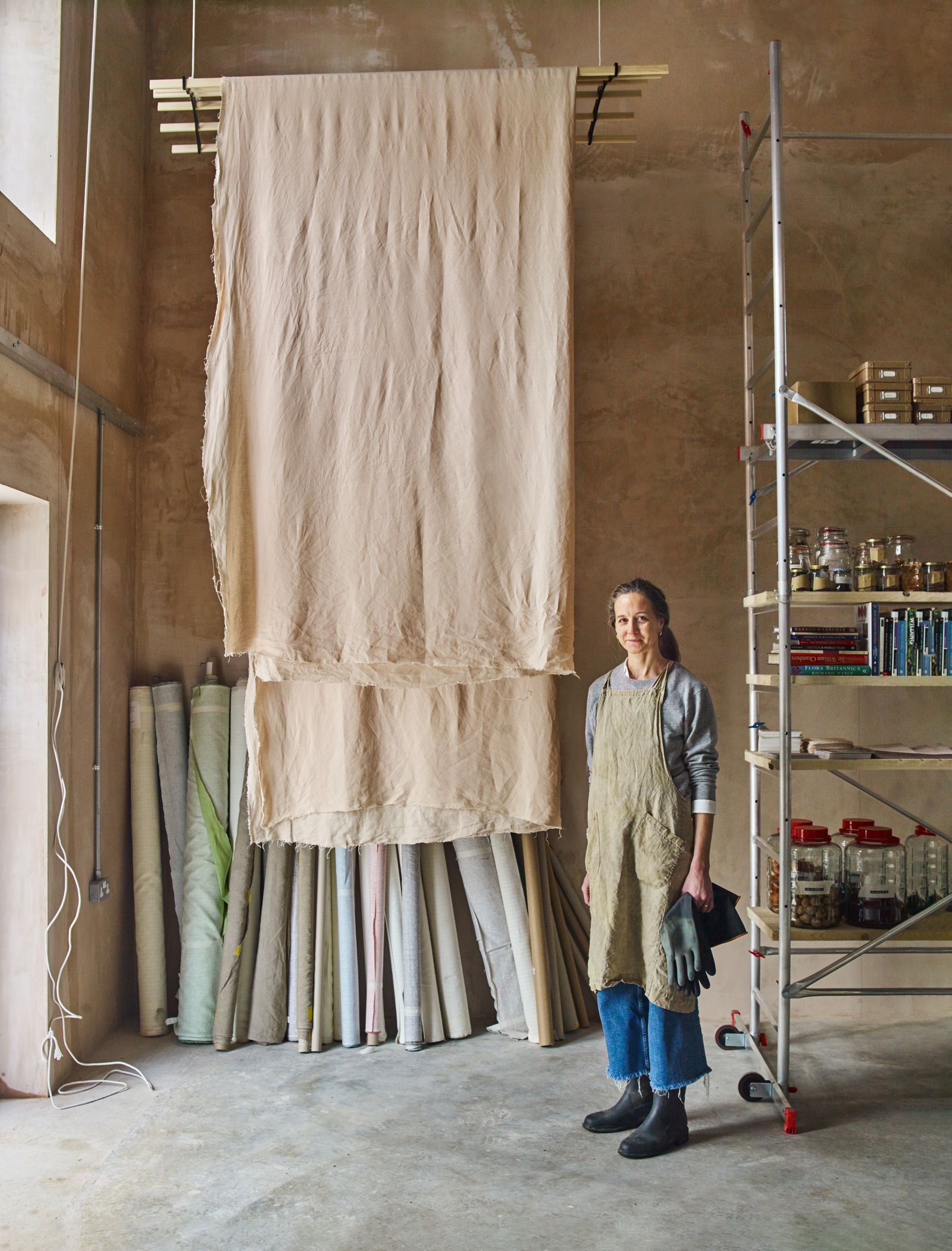 Charlotte in her studio where freshly dyed fabrics dry on racks suspended from the ceiling.