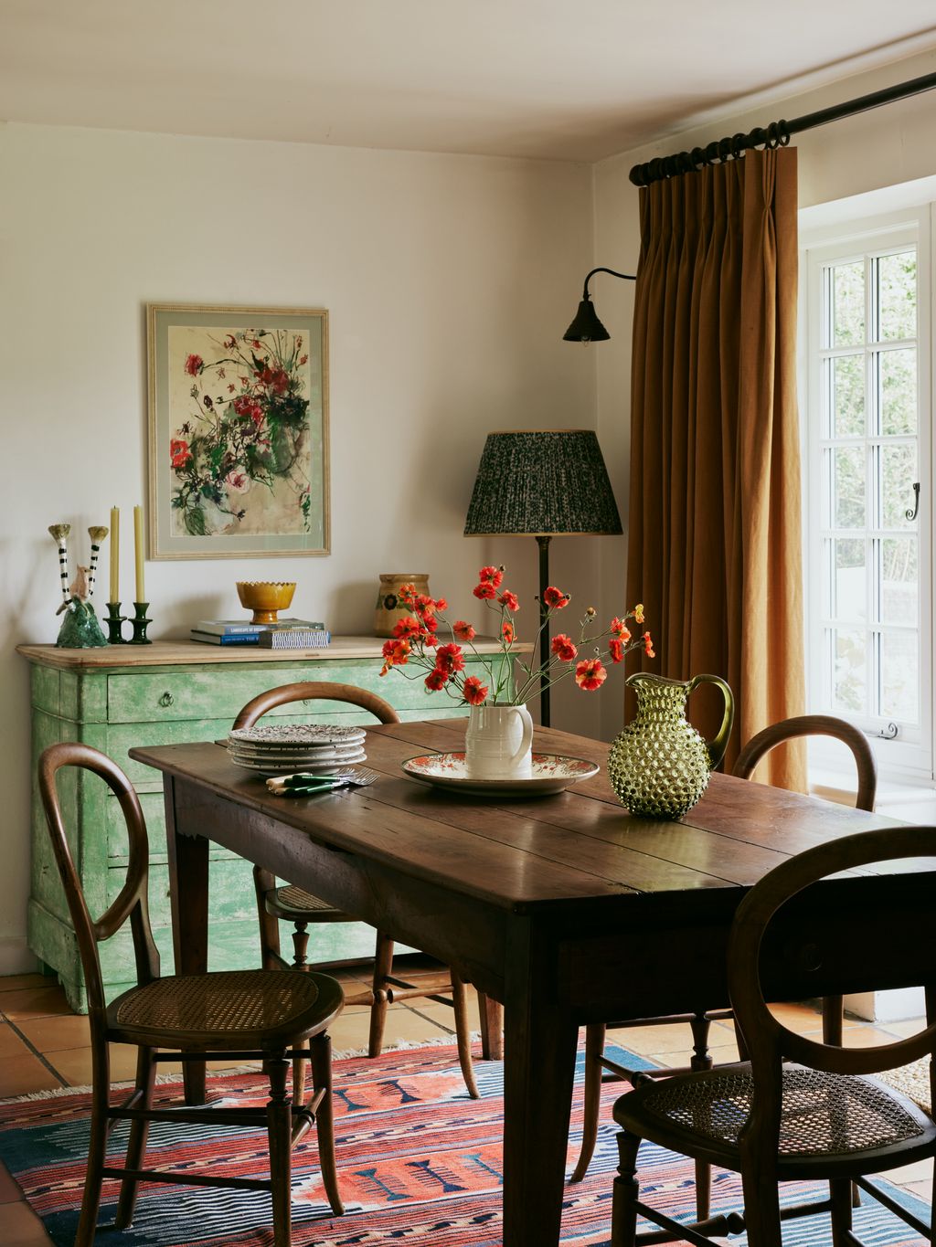 In the dining nook an antique fruitwood 19thcentury dining table sits on a rug from Susan Deliss. The painting above...