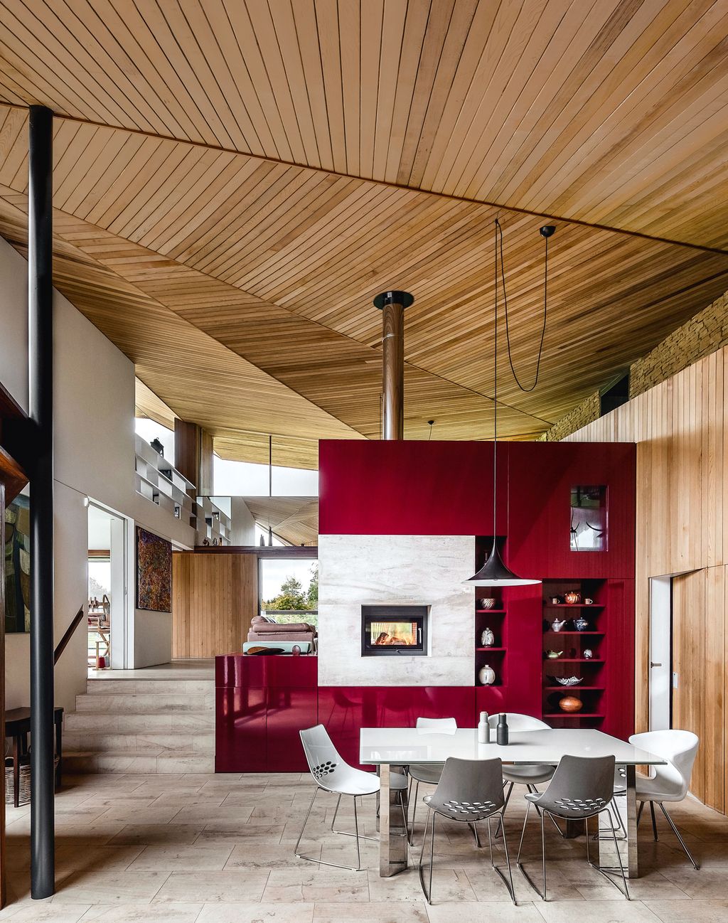 A tall partition housing glossred units open shelving and a twosided fireplace creates a dramatic contrast with the pale...