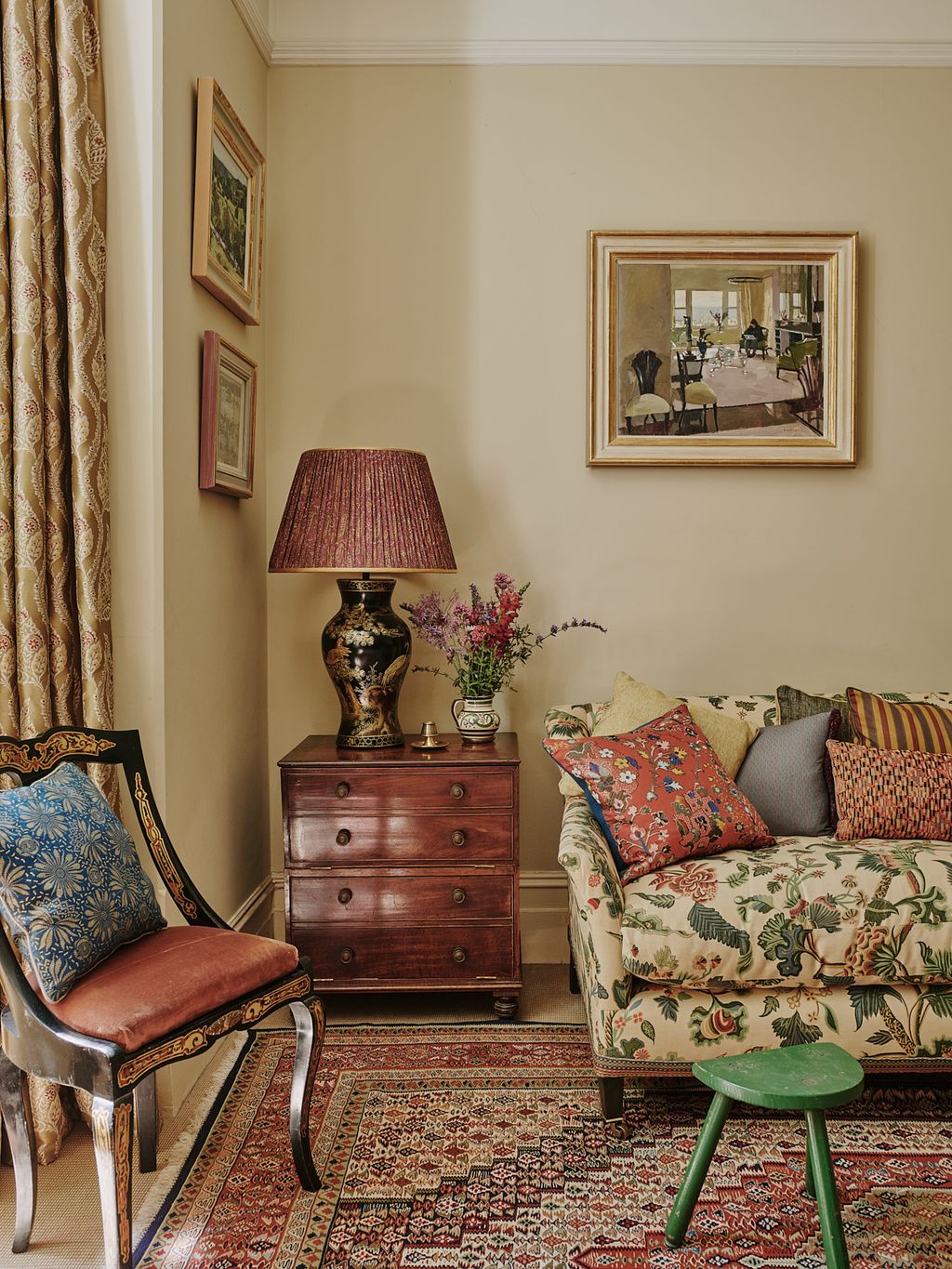 In the drawing room a deep sofa upholstered in Bennison fabric sits beneath a painting by Ken Howard whose soft light...