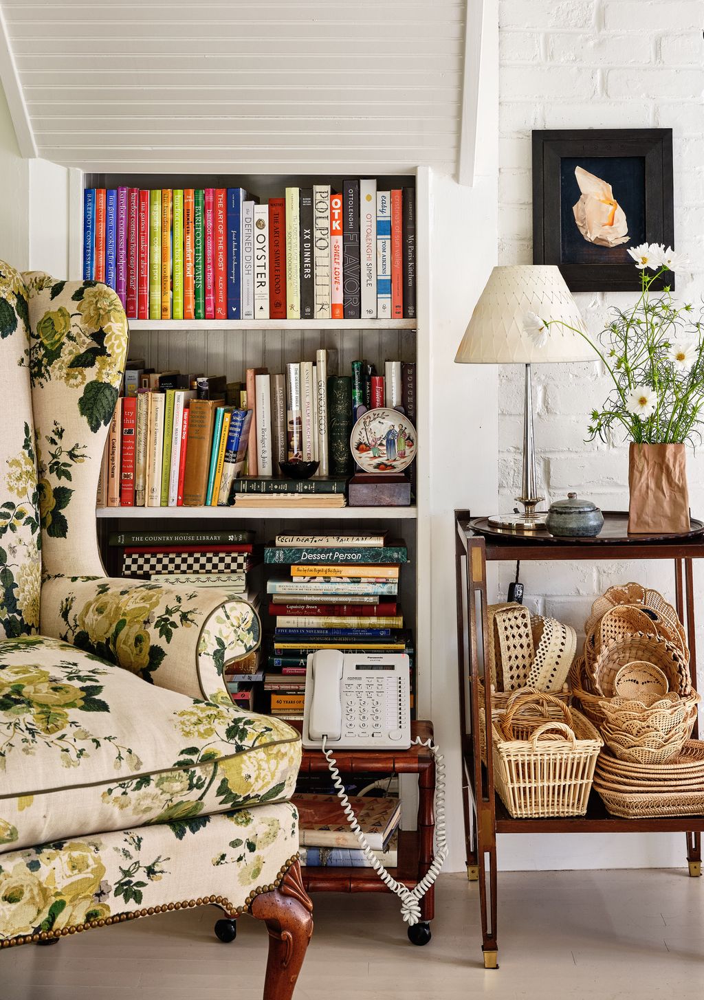 The shelves are stacked with the couple's collection of cookbooks in front of which is a vintage wing chair purchased at...