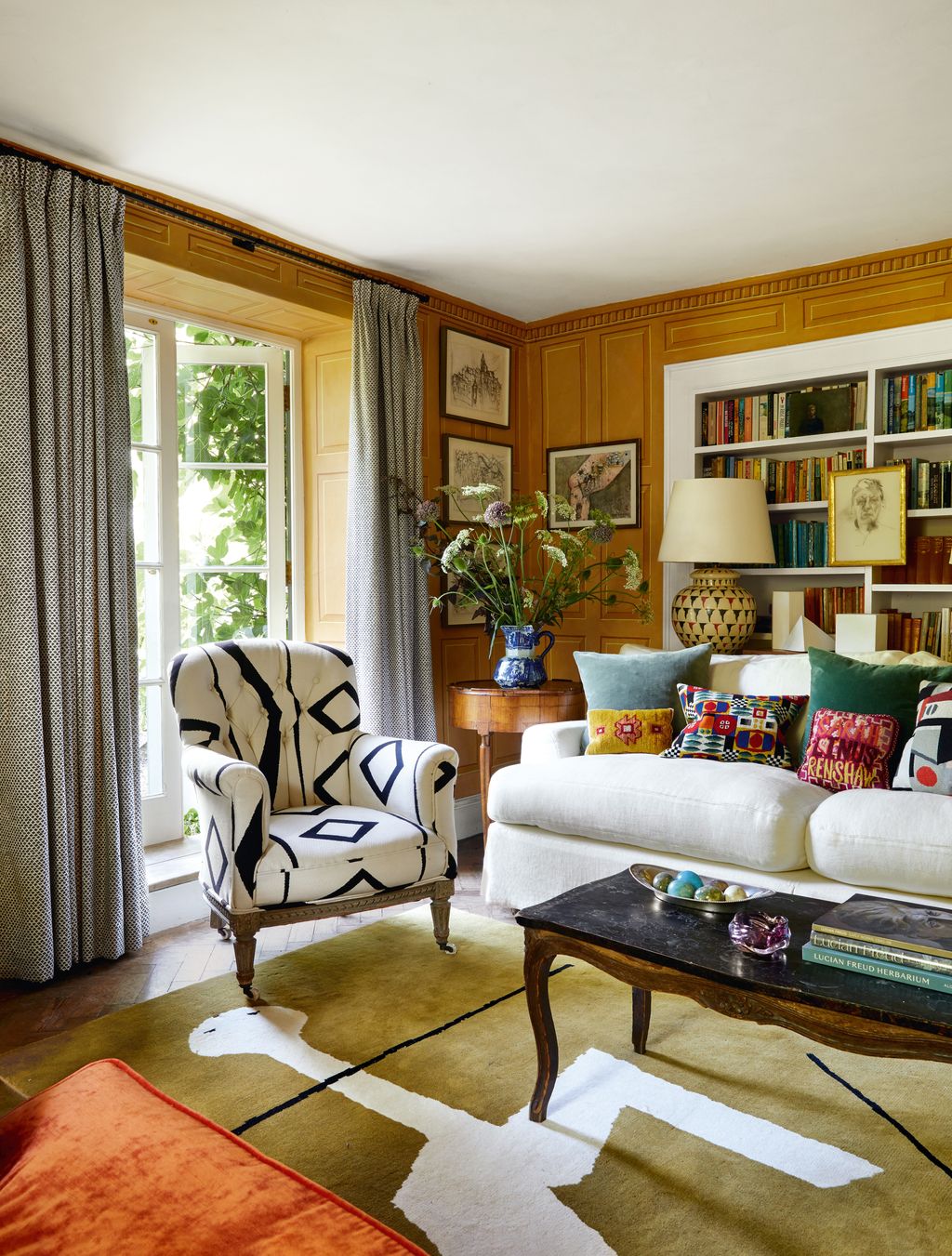 In the sitting room trompe loeil panelling painted by muralist Alan Dodd sets the tone for an elegant artful scheme. The...