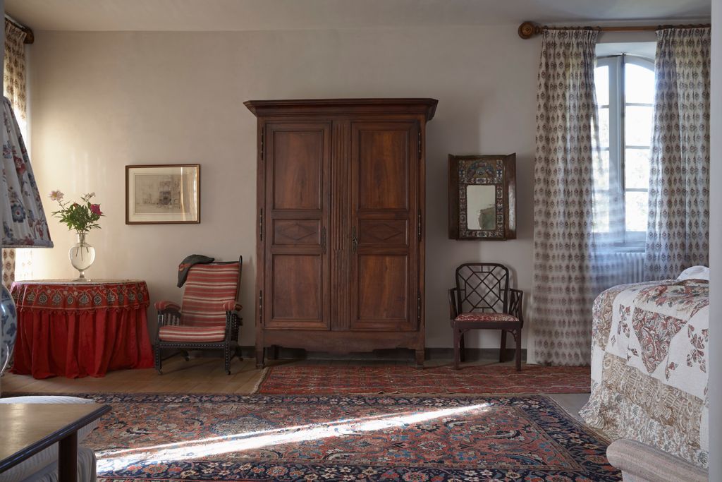 In one of the guest rooms a French armoire takes centre stage flanked by two chairs with a Persian carpet on the floor.